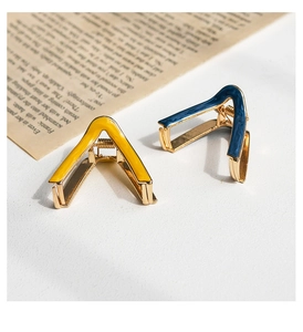 Detailed view of V-shaped metal hair claws in yellow and blue enamel finish