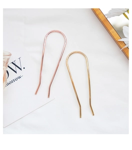 Close-up of minimalist U-shaped metal hairpins in gold and rose gold finishes