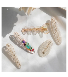 Close-up of five resin hair clips with pearls, crushed shells, and gold foil detailing