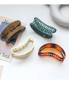 Close-up of four colorful minimalist crescent hair claws on a decorative background