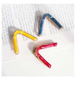 Close-up of three colorful V-shaped metal hair claws on an open magazine background