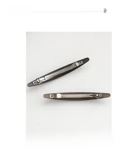 Détail de deux barrettes à ressort marron foncé avec texture fine et base en métal