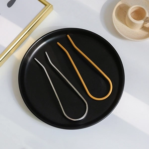 Close-up of minimalist U-shaped metal hairpins in glossy silver and matte yellow finishes