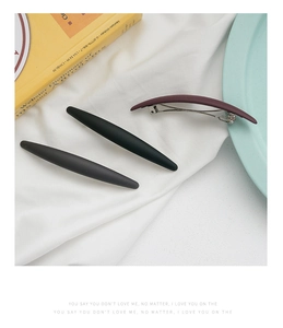 Barrettes à cheveux mates noires, grises et rouge foncé sur un tissu blanc