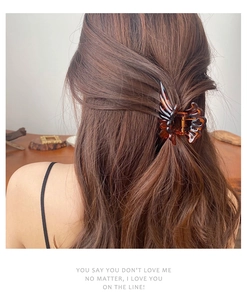 Detail of dark amber resin claw clip holding hair in an elegant updo hairstyle
