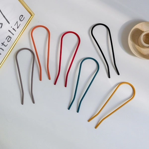 Detailed view of six colorful matte U-shaped hair pins on a decorative ceramic tray