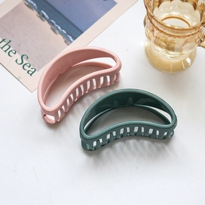 Minimalist half-moon hair claw clips in pink and green colors on a clean white background