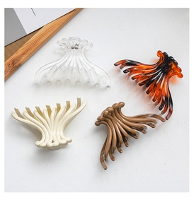 Detail view of four large jelly-style hair claws in clear, amber, cream, and brown colors