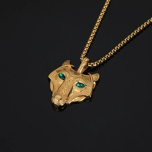 Gold Viking wolf head pendant necklace with green eyes and box chain on black reflective base