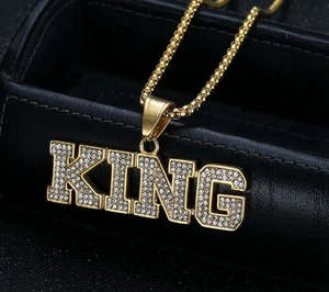 Μακρο φωτογραφία του επίχρυσου μενταγιόν KING με κρύσταλλα σε μαύρο δέρμα