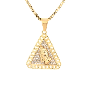 Macro detail of gold prayer hands pendant with sparkling crystals and box chain