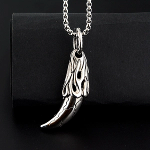 Detailed macro view of retro wolf tooth pendant with flame relief and silver box chain