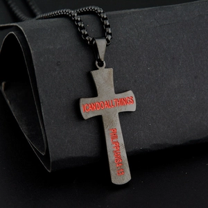 Gros plan du pendentif croix en acier noir mat avec verset Philippiens 4:13 en rouge