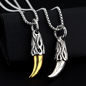 Detailed close-up of gold and silver wolf tooth pendants with flame relief on box chains