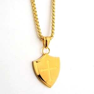 Close-up of golden shield pendant necklace with cross symbol and square box chain detail