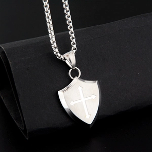 Close-up of vintage shield cross pendant with box chain on elegant black background