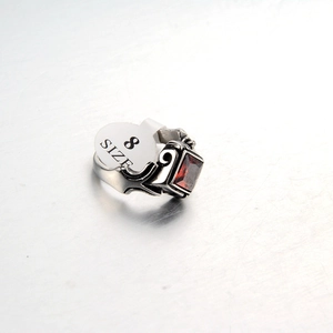 Detail view of gothic steel ring with red square gemstone and size 8 tag