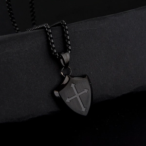 Detail of a vintage black shield pendant with a cross on a sturdy box chain necklace