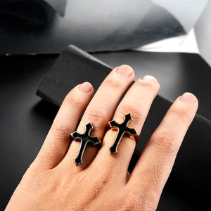 Close-up of punk style cross rings in black gold and silver finishes on finger