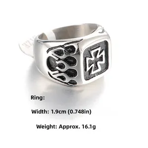 Close-up of punk steel ring showing embossed iron cross and flame patterns on the side