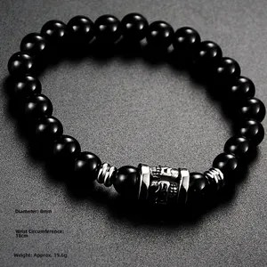 Detailed close-up of 8mm black beaded bracelet with silver mantra charm on stone background
