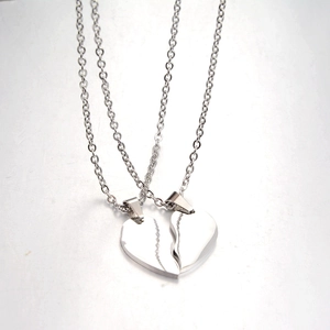 Polished stainless steel couple necklaces with split heart pendant on gray background