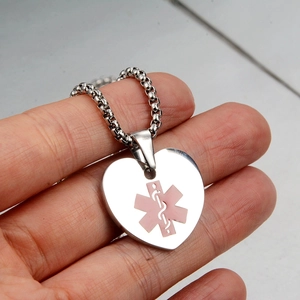 Detailed close-up of heart medical ID pendant with pink Caduceus star and bead chain