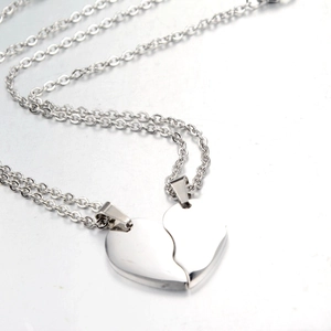 Detailed close-up of matching silver heart pendant necklaces for couples in polished steel