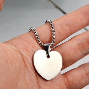 Detail of heart pendant with brushed metal finish on a classic box chain necklace