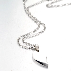 Detailed view of polished silver half-heart pendant on thin stainless steel O-chain link