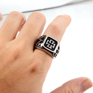 Close-up of vintage steel ring with embossed iron cross and flame texture on hand