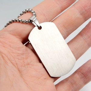 Close-up of silver brushed steel medical tag pendant with ball chain held in hand