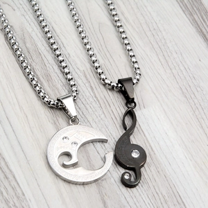 Détail des pendentifs couple lune argentée et note de musique noire avec gravure
