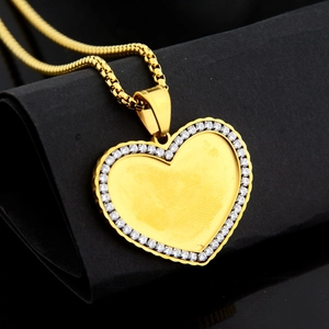Elegante collana con medaglione a cuore dorato e strass scintillanti su sfondo nero espositivo