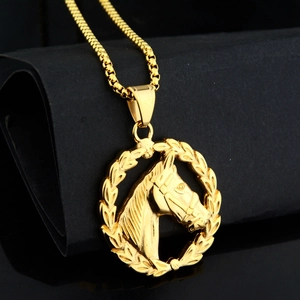 Vue macro du pendentif relief tête de cheval doré sur surface noire avec chaîne box