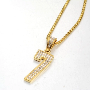 Detalle macro del collar con colgante de número 7 dorado con piedras de circón brillantes