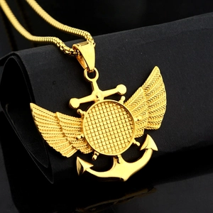 Vue macro du pendentif aile ancre dorée avec motif grille sur socle noir
