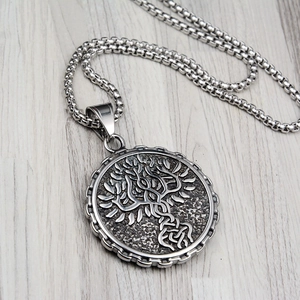 Silver stainless steel tree of life medallion pendant necklace on a wooden background
