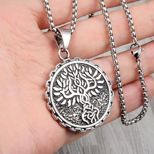 Detail showing the intricate Tree of Life engraving on a silver stainless steel pendant