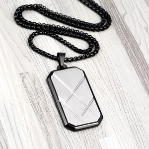 Macro shot of industrial square pendant with diagonal stripes on a black box chain