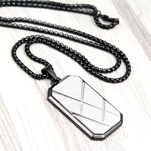 Macro detail of men's square pendant necklace with striped brushed metal finish
