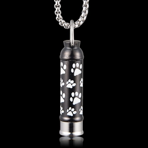 Macro detail of black stainless steel cylinder urn necklace with white paw prints pattern