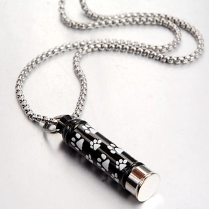 Macro shot of black stainless steel cremation pendant with white paw prints and silver chain