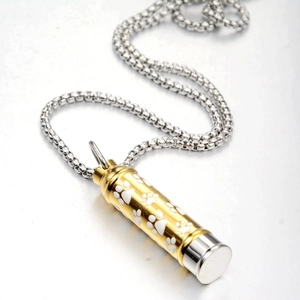 Detail of cylinder cremation urn necklace with gold and silver tone puppy paw prints