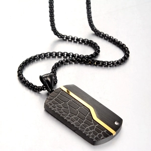 Macro detail of men's dog tag necklace with black faux leather texture and gold accents