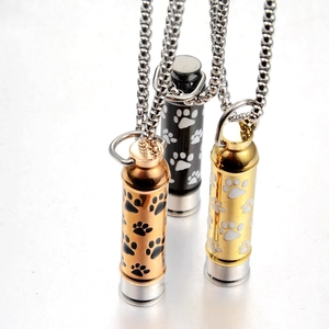 Three cylindrical pet urn necklaces in gold, rose gold, and black with paw prints