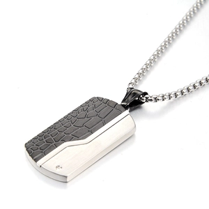 Detailed macro view of rectangular dog tag pendant with textured black and silver steel