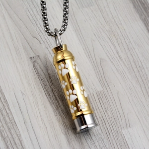Detailed macro view of cylinder pet urn necklace with paw prints and silver square chain
