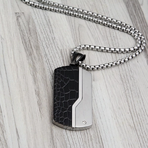 Detail of military dog tag pendant with black crocodile texture and inlaid crystal