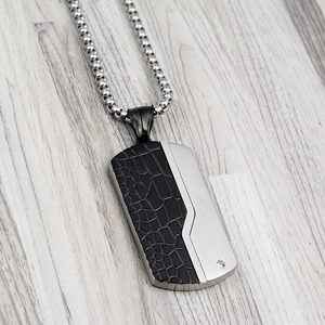 Detail of dog tag pendant with black leather texture and polished steel with a crystal